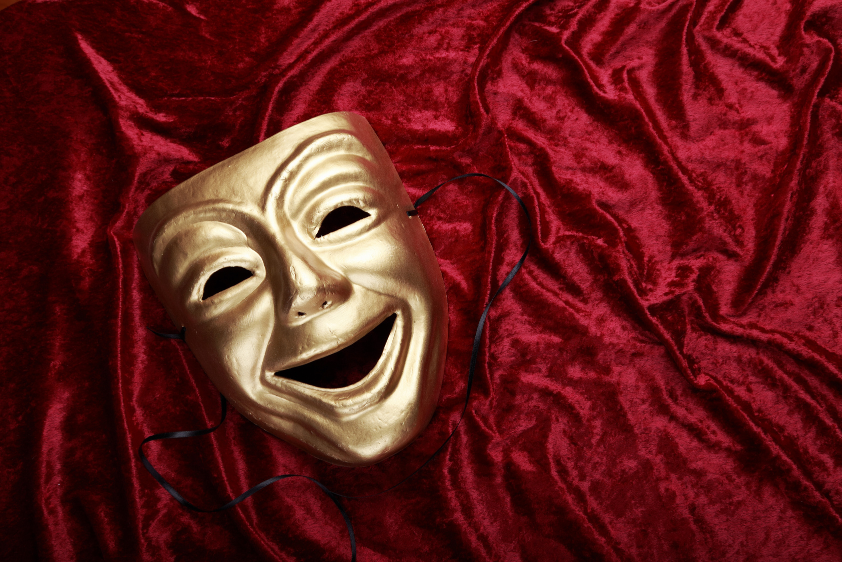 Classical theater comedy mask on a velvet curtain